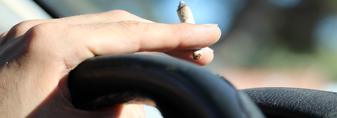 person holding rolled cigarette and driving