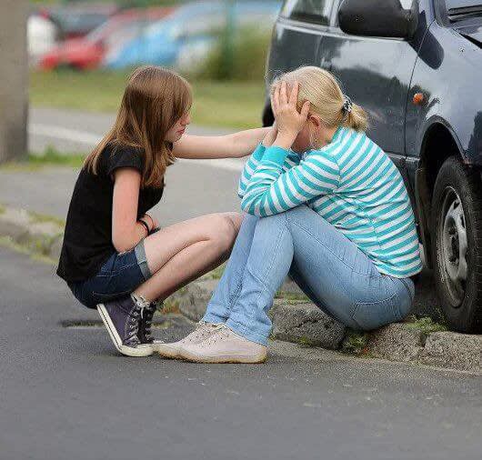 Woman and daughter sitting next to car after an accident