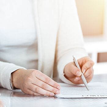 Woman holding a pen with a white cardigan