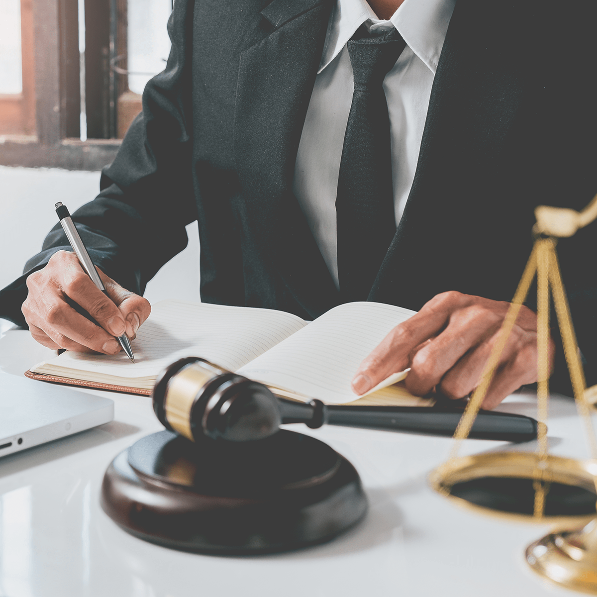 Male judge working with contract papers on white wooden table in courtroom. Laptop computer, legal books and gavel on white desk. justice and law concept