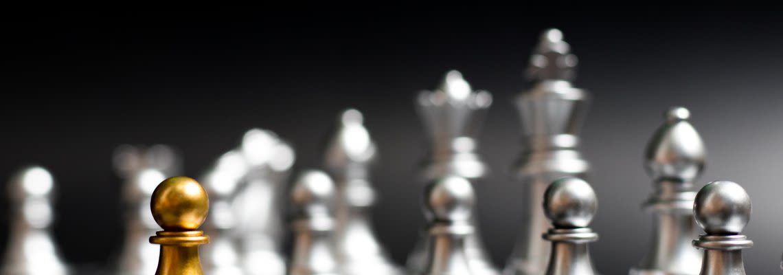gold pawn next to silver pieces
