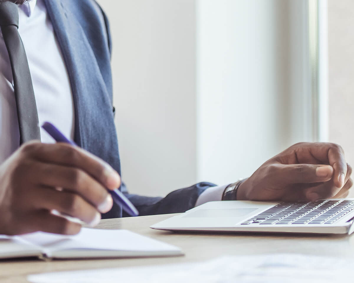 Business man holding a pen while working on laptop