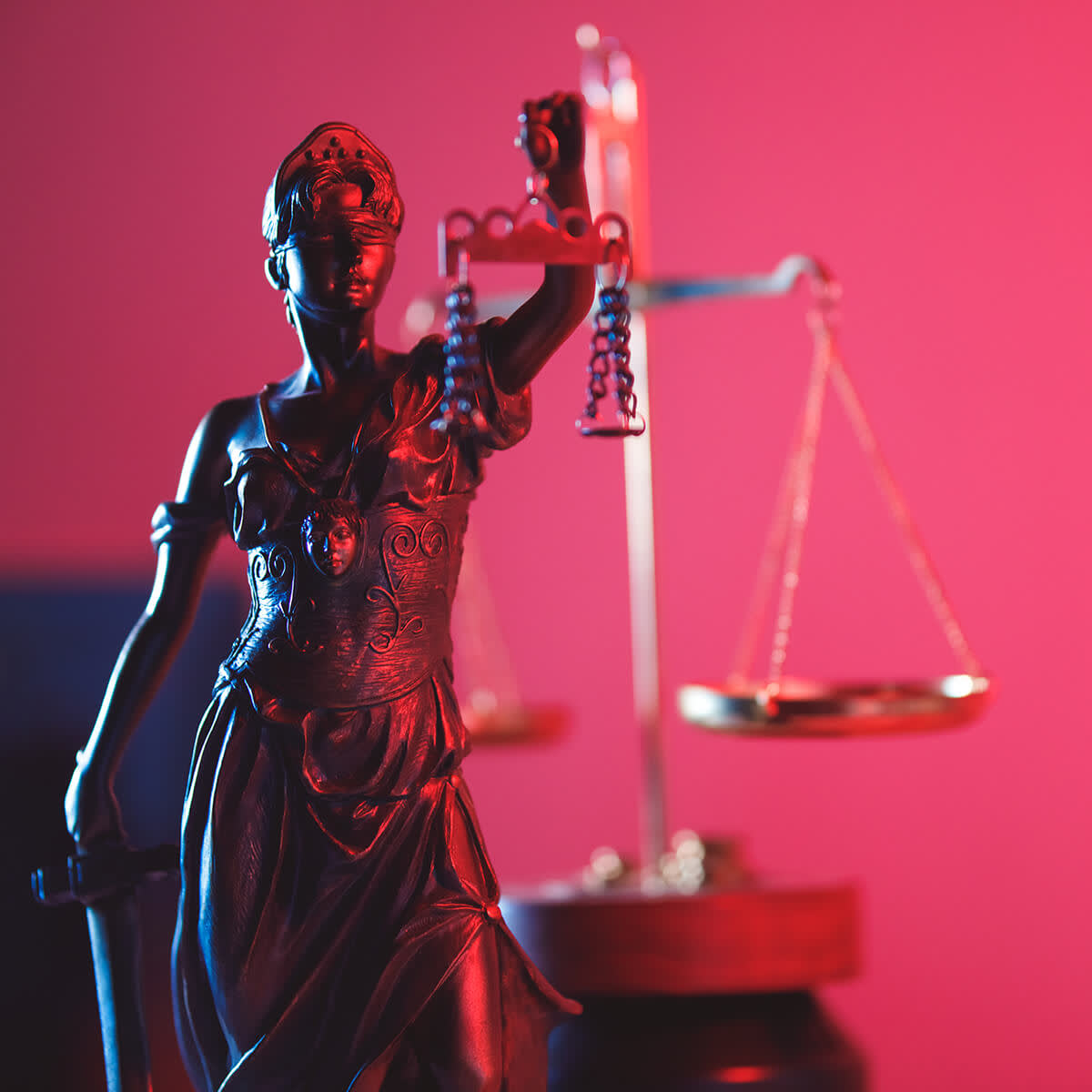 Lady of Justice statue in red neon lighting