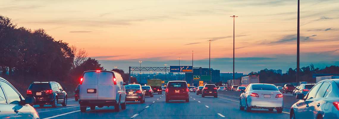 Multiple cars driving on highway at sunset