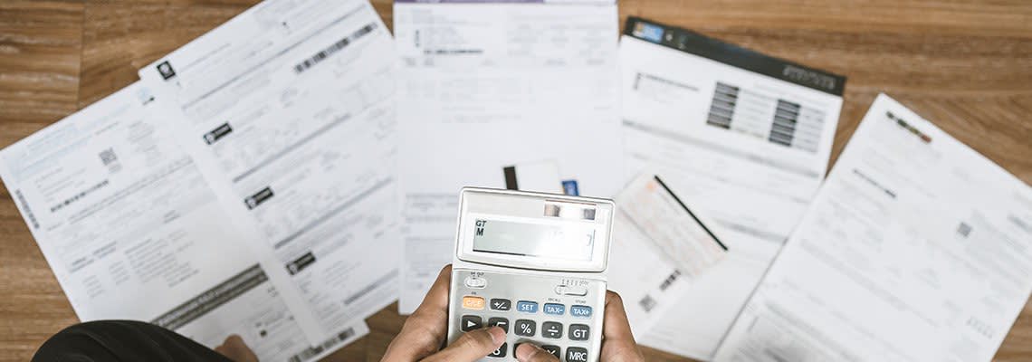 Finical documents on the ground, someone holding a calculator