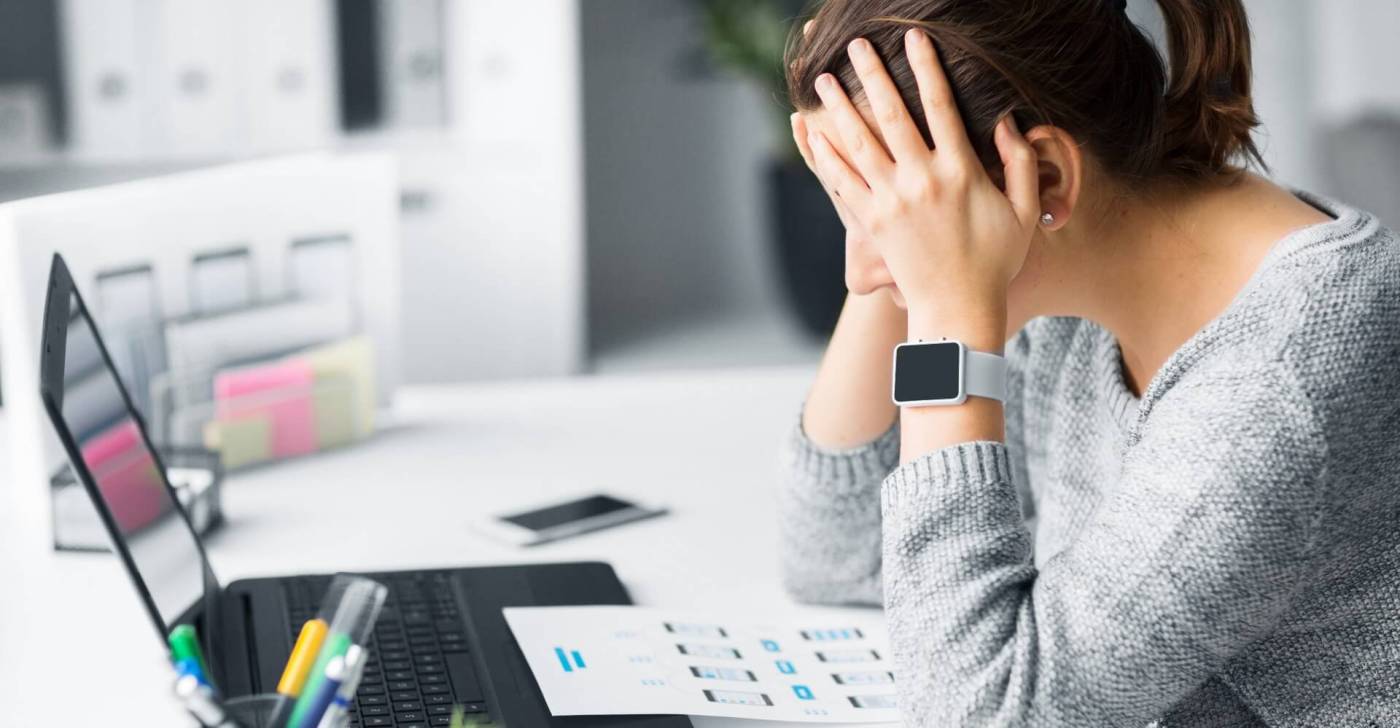 Stressed businesswoman sitting at desk staring at a laptop.jpg