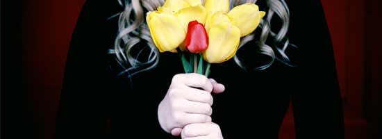 A person in black holding yellow and red tulips