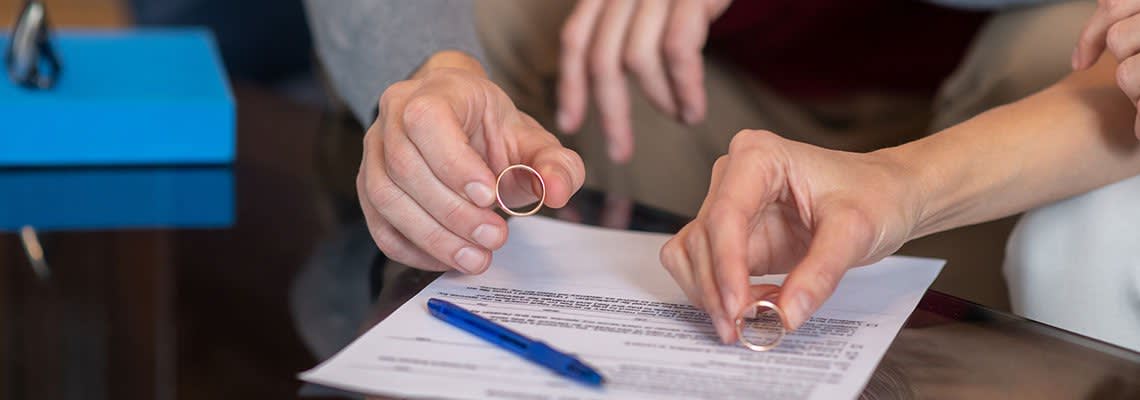 Couple signing documents and taking off wedding rings
